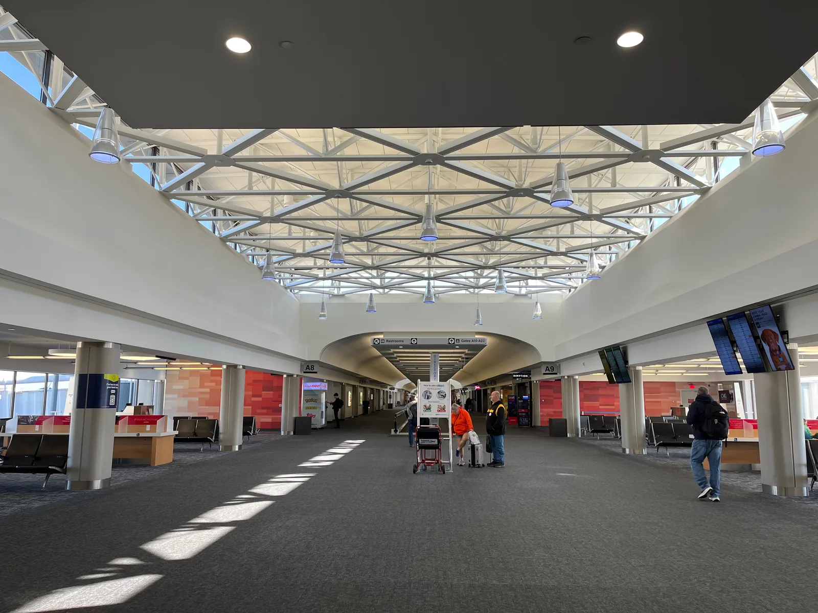 A concourse at Cincinnati/Northern Kentucky International Airport under its white truss roof, with the gates down either side.