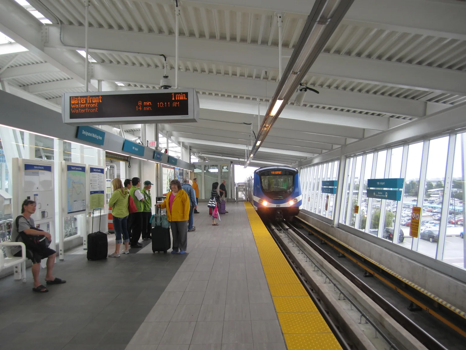 A Canada Line train arriving at YVR-Airport station, with passengers waiting on the platform.