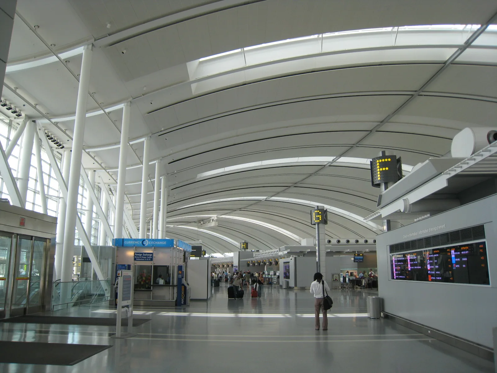 The vaulted departures hall at Toronto Pearson Terminal 1, with flight information boards along the concourse.