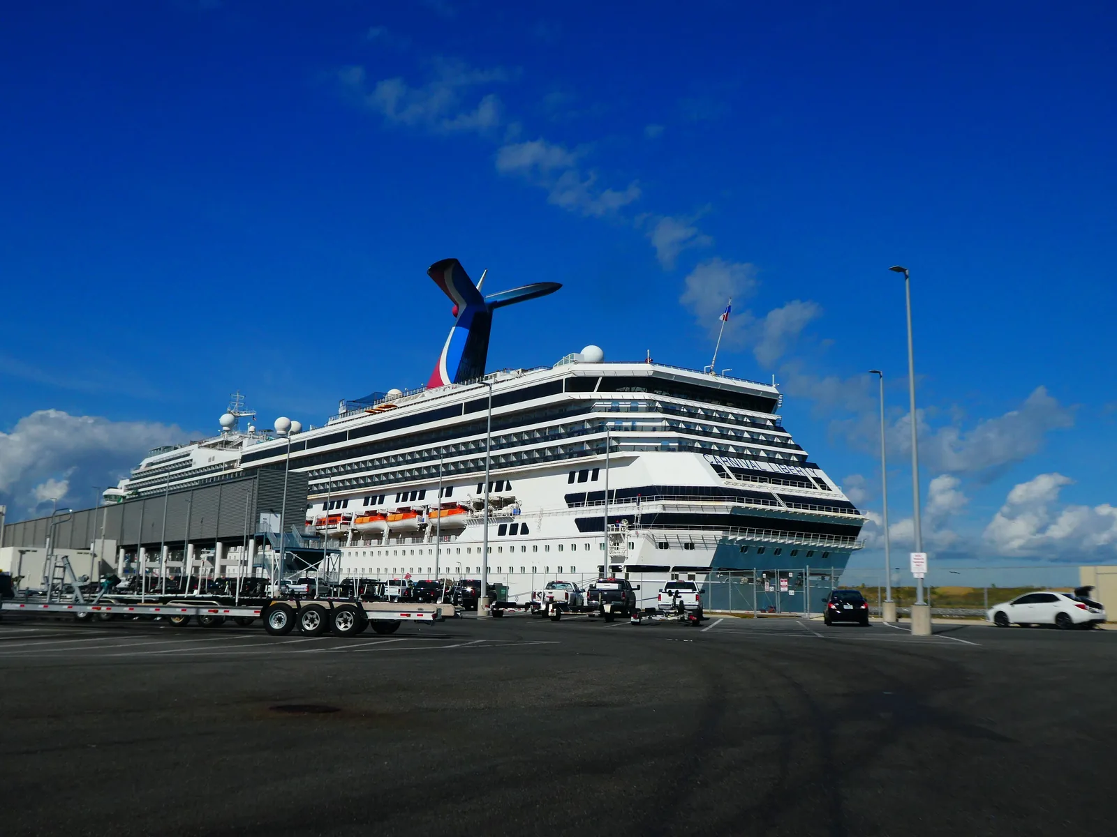 A Carnival ship docked at its terminal in Port Canaveral, seen from the parking lot.