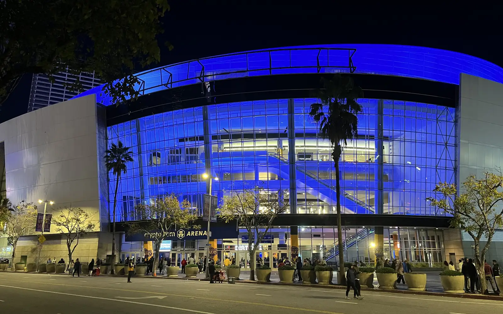 Crypto.com Arena in Los Angeles lit at night, the curved glass frontage onto the L.A. Live plaza.