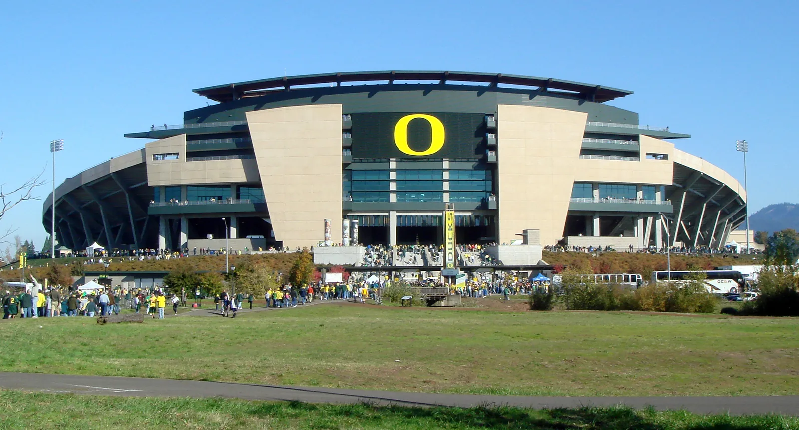 Autzen Stadium in Eugene, Oregon, with the Oregon O on its facade and fans walking in.