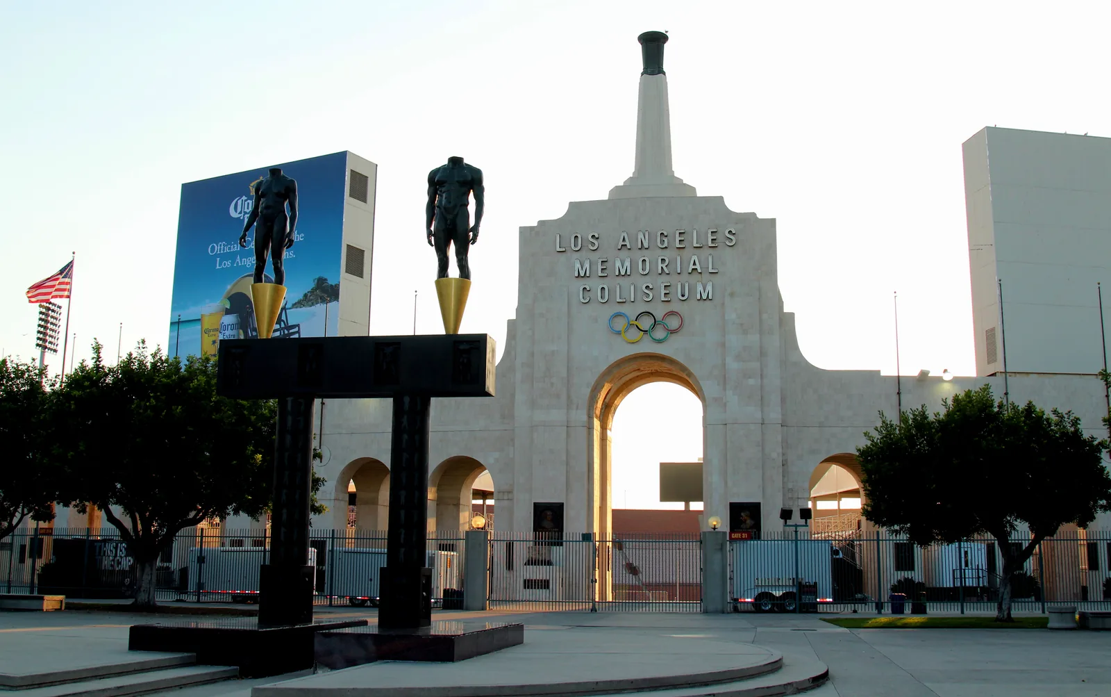 The peristyle arches and Olympic torch at the east end of the Los Angeles Memorial Coliseum, with the Olympic Gateway statues in front.