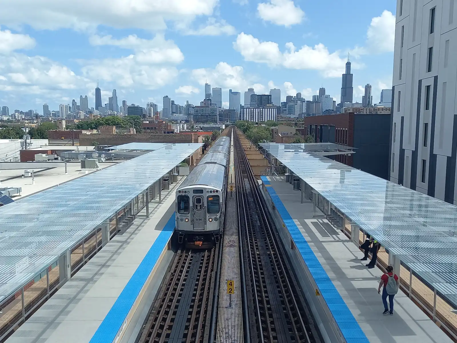 A Green Line train pulling into Damen station, with the Chicago skyline behind it. The arena is two blocks from here.