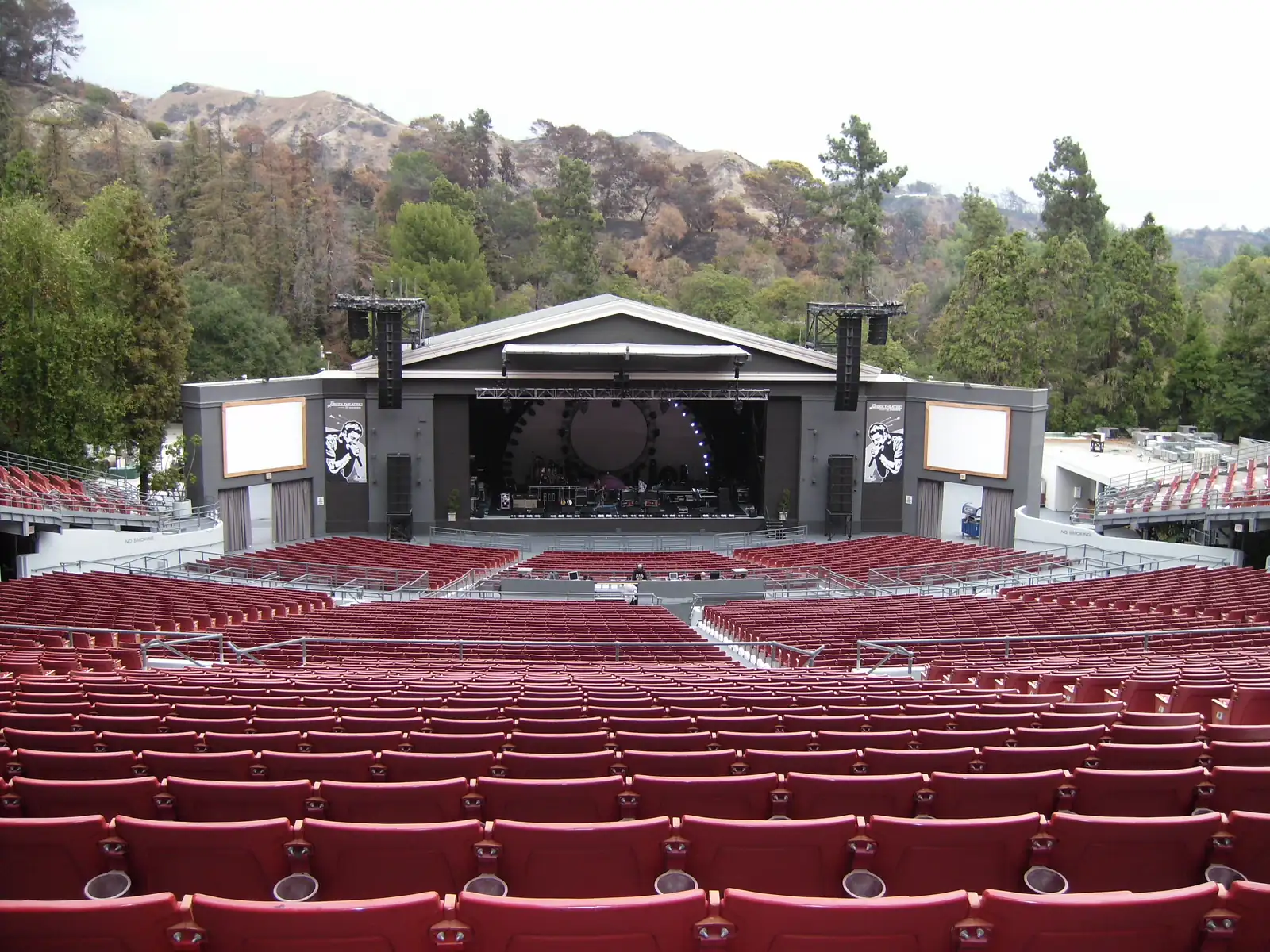 The Greek Theatre seen from the back of the terraces, empty, the stage below and Griffith Park rising behind it