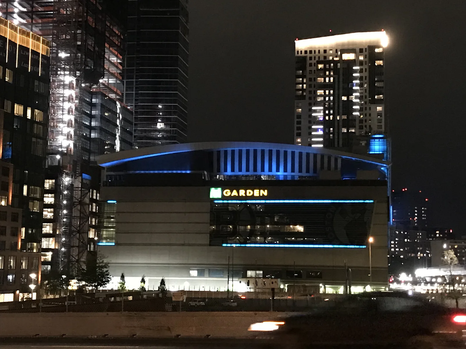 TD Garden lit blue at night above Causeway Street, with the arena name across the front of the building.