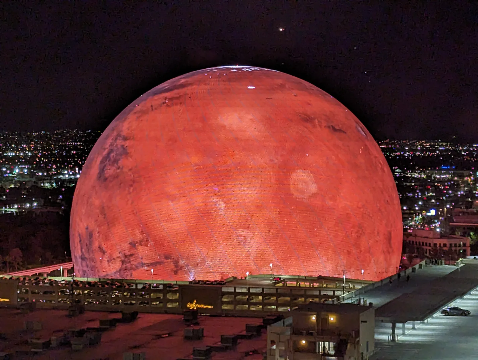 The Sphere in Las Vegas at night, its exterior LED screen lit as the planet Mars above the city.